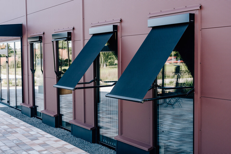 © Becker-Antriebe GmbH Fallarmmarkisen an den Fenstern automatisiert mit Antriebs- und Steuerungstechnik von Becker für blendfreien, energieeffizienten Sonnenschutz. 