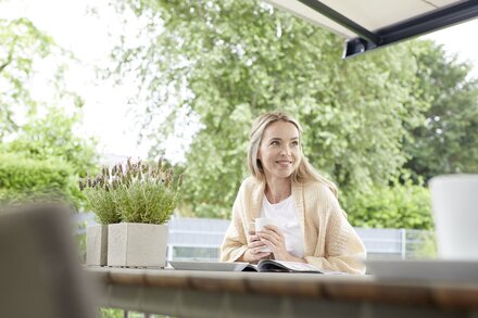 Frau genießt den Sommer auf der Terrasse mit einer Markise
